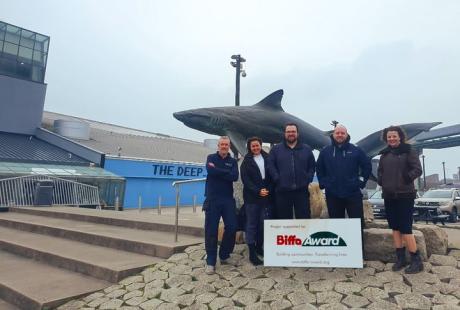 members of The Deep crew and Biffa stood outside The Deep with the shark statue