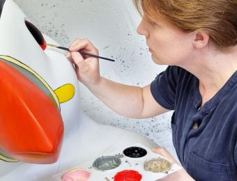 Artist Tracy Willis painting the eye of the puffin sculpture