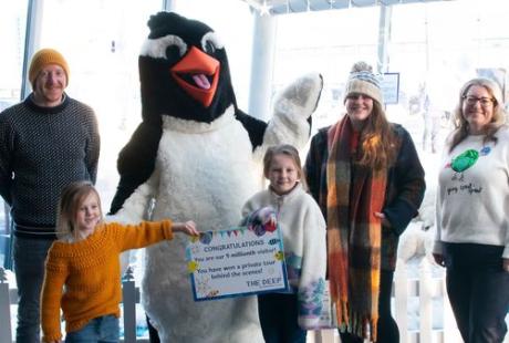 A family having their photo taken with someone dressed up in a penguin costume